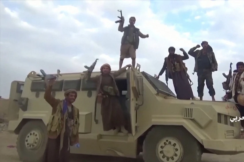Các tay súng Houthis bên cạnh một xe quân sự của Saudi Arabia. Ảnh: REUTERS