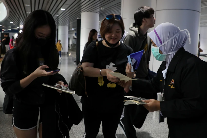 Nhân viên y tế Malaysia phân phát tờ rơi về virus corona cho hành khách tại sân bay quốc tề Kuala Lumpur (Malaysia) ngày 21-1. Ảnh: REUTERS