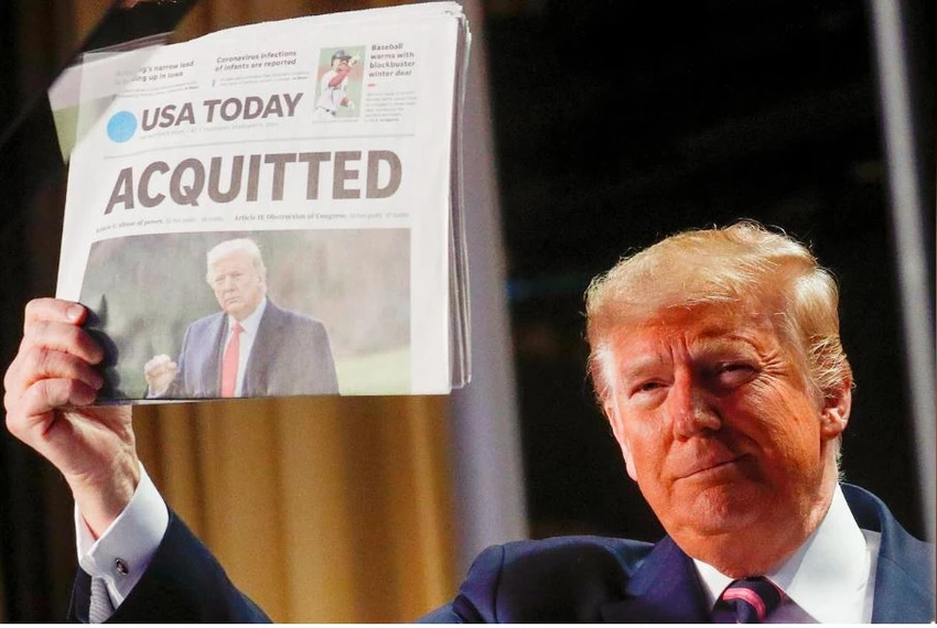 Tổng thống Mỹ Donald Trump cầm một tờ báo USA Today đưa tin ông được Thượng viện tuyên trắng án, khi phát biểu tại buổi lễ ăn sáng cầu nguyện quốc gia thường niên ở thủ đô Washington (Mỹ) ngày 6-2. Ảnh: REUTERS