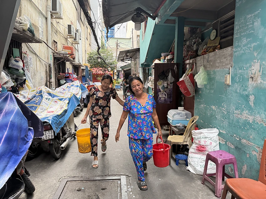 Từ khi có căn cước, bà Trần Thị Kim Bông (phải, người dân sống hẻm 27 Nguyễn Thái Bình) không còn phải mua nước sinh hoạt theo từng xô mỗi ngày. Ảnh: HUỲNH THƠ