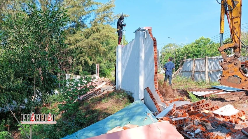 Tháo dỡ phần hàng rào bằng tường gạch. Ảnh: NT