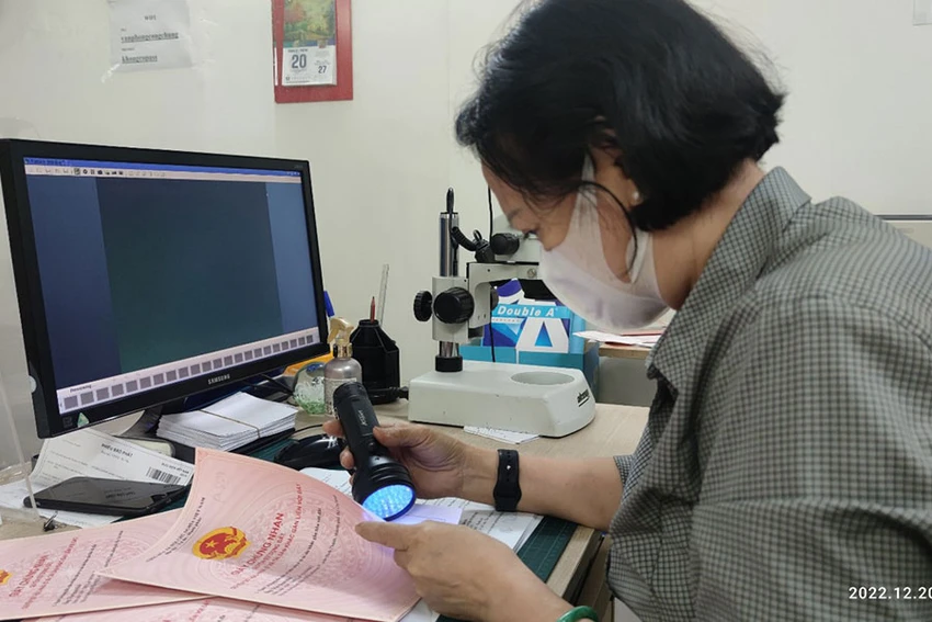 Công chứng viên đang kiểm tra giấy tờ tùy thân khi công chứng hợp đồng. Ảnh: NGUYỄN HIỀN