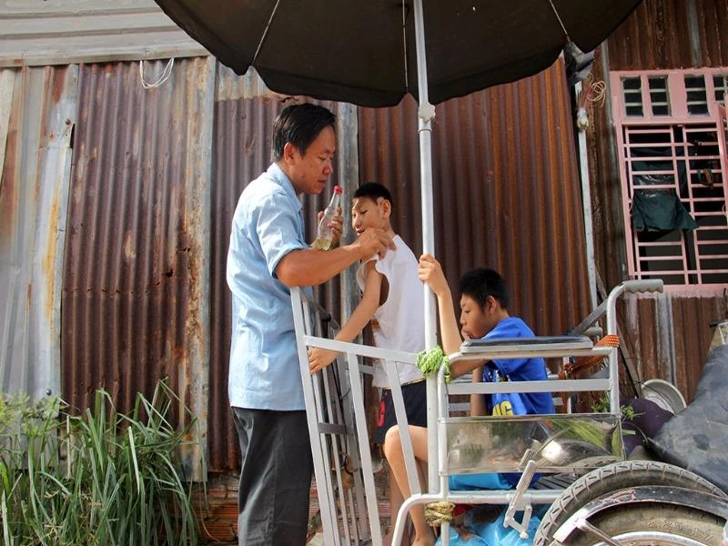 Anh Nghị bôi dầu cho con khỏi bị muỗi cắn trước khi bắt đầu hành trình bán kẹo mưu sinh.