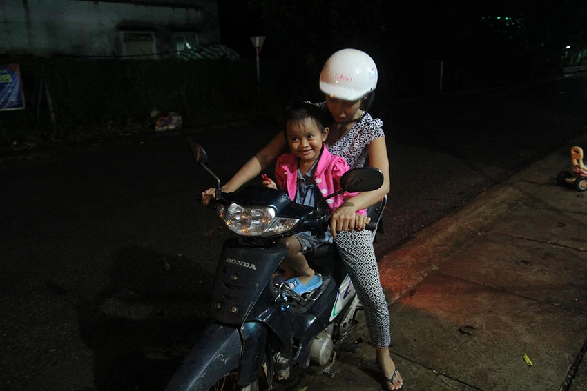 Bé Lan Anh được mẹ nuôi Thu Trang chở đi chợ trong lần về thăm nhà cũ. Ảnh: HOÀNG GIANG