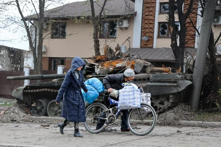 Dân thường Ukraine đi ngang qua một chiếc xe tăng bị phá hủy trong cuộc giao tranh ác liệt ở Mariupol, ngày 19-4-2022. Ảnh: AP Dân thường Ukraine đi ngang qua một chiếc xe tăng bị phá hủy trong cuộc giao tranh ác liệt ở Mariupol, ngày 19-4-2022. Ảnh: AP