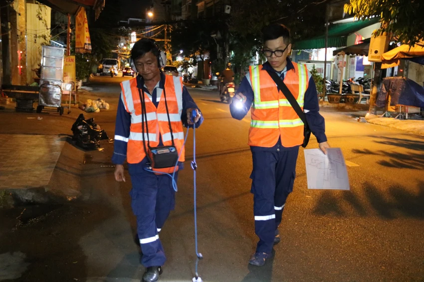 Công nhân vừa di chuyển, vừa đeo thiết bị dò tìm đường ống nước bể.