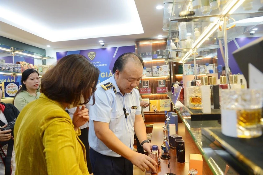 Tổng cục trưởng Tổng cục QLTT Trần Hữu Linh hướng dẫn người dân cách phân biệt hàng thật với hàng vi phạm. Ảnh: AH