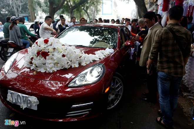 Chiếc xe Porsche màu đỏ được sử dụng làm xe rước dâu. Tuấn Hưng đề nghị trang trí xe hoa bằng lan trắng và hồng đỏ. Biển xe được thay bằng tấm bảng dễ thương với chữ "Love" ánh bạc. Nhập mô tả cho ảnh