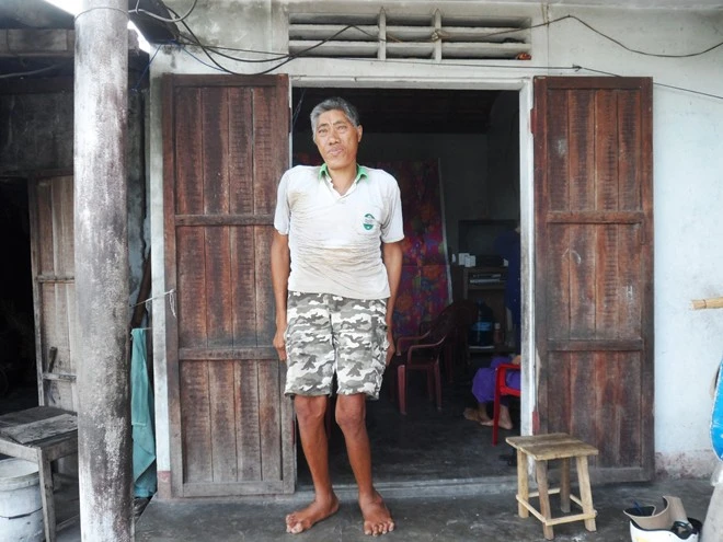 Ông Chính đứng đụng trần cửa nhà. Dù bị còng lưng nhưng ông Chính đứng thẳng vẫn cao gần bằng cửa nhà 2m