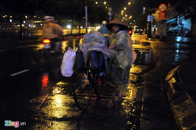 Cuối ngày, gia tài của người lượm ve chai ở đường Võ Văn Kiệt (quận 6) chất xiêu vẹo trên chiếc xe đạp cũ. Một người phụ nữ dắt xe dưới trời mưa trên đường Võ Văn Kiệt (quận 6).