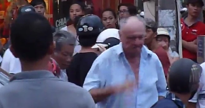 Ông Dennis bỏ đi sau khi gây náo loạn đường phố Đà Nẵng.Ảnh cắt từ clip. Ông Dennis là nghi can bị tố xé phù hiệu taxi, xù tiền, hành hung tài xế taxi Nguyễn Quý (47 tuổi, trú quận Hải Châu) và đã đánh gãy mũi chị Trang gây náo loạn đường phố Đà Nẵng. Ảnh cắt từ Clip.