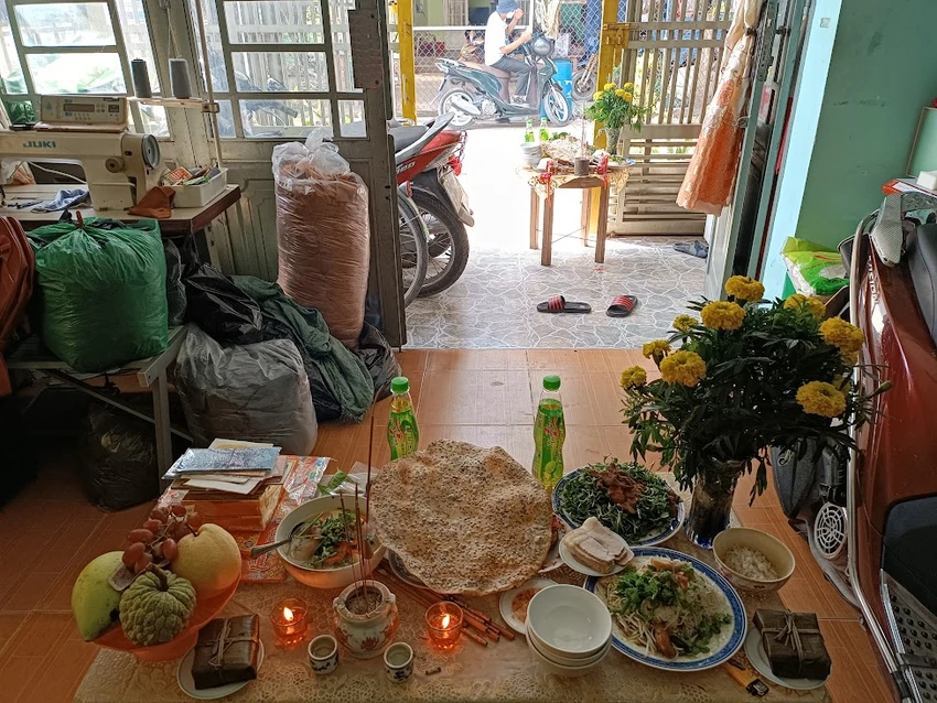 Gia chủ bày biện mâm cúng giữa nhà nhìn từ trong nhà ra ngoài sân