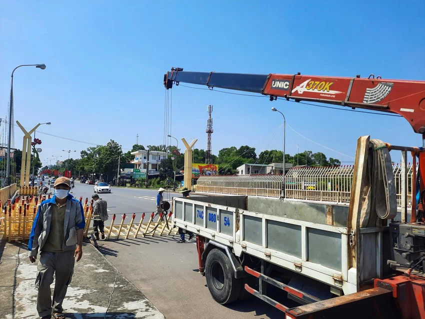 Công nhân tiến hành tháo dỡ những thanh sắt đã lắp đặt dọc bên lan can cầu Đại An.Dưới cái nắng chói chang, gần 10 nhân công có mặt để thực hiện việc tháo dỡ.