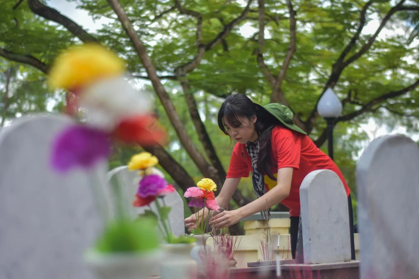Một nữ sinh chỉnh sửa lại những bông hoa trên mộ của các liệt sĩ. Ảnh: NGUYỄN DO