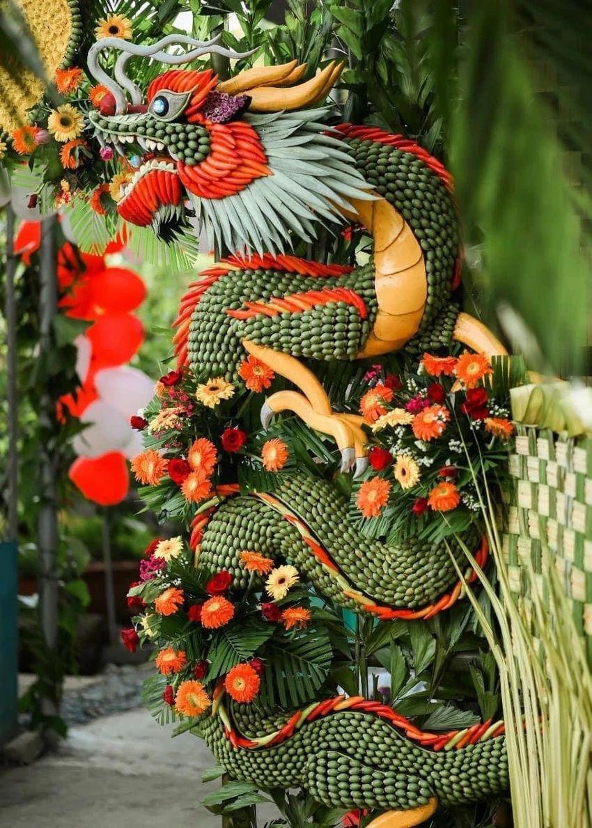 Thân con vật sẽ dùng các quả cau xếp san sát nhau, vây lưng dùng ớt sừng đỏ cho đẹp mắt, lá dừa đan xen làm bờm, đuôi, tỏi làm hàm răng và đậu đũa để viền đôi mắt, làm râu, miệng. Ngoài ra, anh Tâm sử dụng thêm hoa cúc, hoa đồng tiền để tô điểm thêm phần cánh cho rực rỡ. Thân con vật sẽ dùng các quả cau xếp san sát nhau, vây lưng dùng ớt sừng đỏ cho đẹp mắt, lá dừa đan xen làm bờm, đuôi, tỏi làm hàm răng và đậu đũa để viền đôi mắt, làm râu, miệng. Ngoài ra, anh Tâm sử dụng thêm hoa cúc, hoa đồng tiền để tô điểm thêm phần cánh cho rực rỡ.