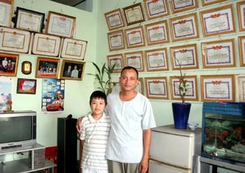 "Hiệp sĩ đường phố" cùng cậu con trai 10 tuổi trong căn nhà khoảng 30 m2 treo trên 100 bằng khen mang tên anh. Ảnh: An Nhơn. "Hiệp sĩ đường phố" cùng cậu con trai 10 tuổi trong căn nhà khoảng 30 m2 treo trên 100 bằng khen mang tên anh. Ảnh: An Nhơn.