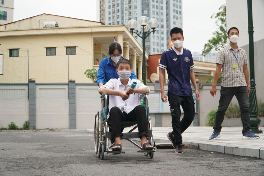 Tình nguyện viên hỗ trợ đưa đón Quyền tại điểm thi. Ảnh PHI HÙNG