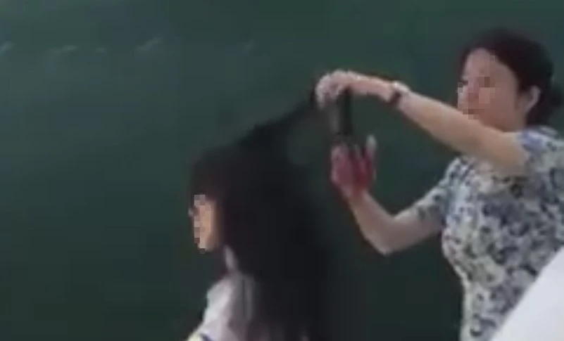 Hình ảnh nữ giáo viên cắt tóc nữ sinh trên lớp. Ảnh: Cắt từ clip Hình ảnh nữ giáo viên cắt tóc nữ sinh trên lớp. Ảnh: Cắt từ clip