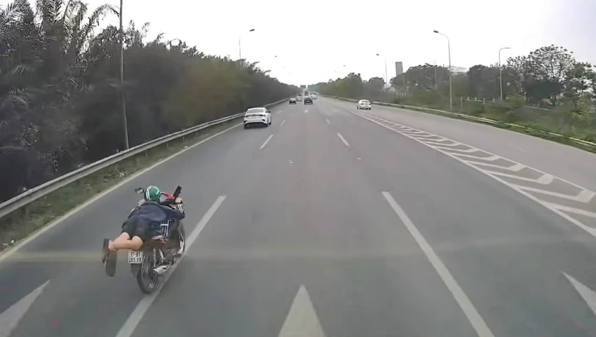 Nam thanh niên nằm trên yên xe máy vượt ô tô trên Đại lộ Thăng Long