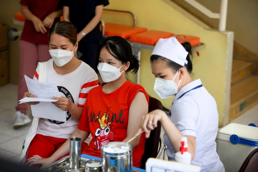 Phụ huynh và học sinh tại điểm tiêm Trường tiểu học đang chờ tiêm vắc xin COVID-19 sáng 16-4.