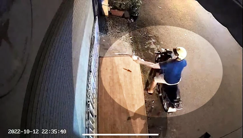 Tiếp đó, một người thanh niên cũng đi xe máy tới tạt sơn, nhớt, mắm tôm vào căn nhà. Ảnh chụp từ clip