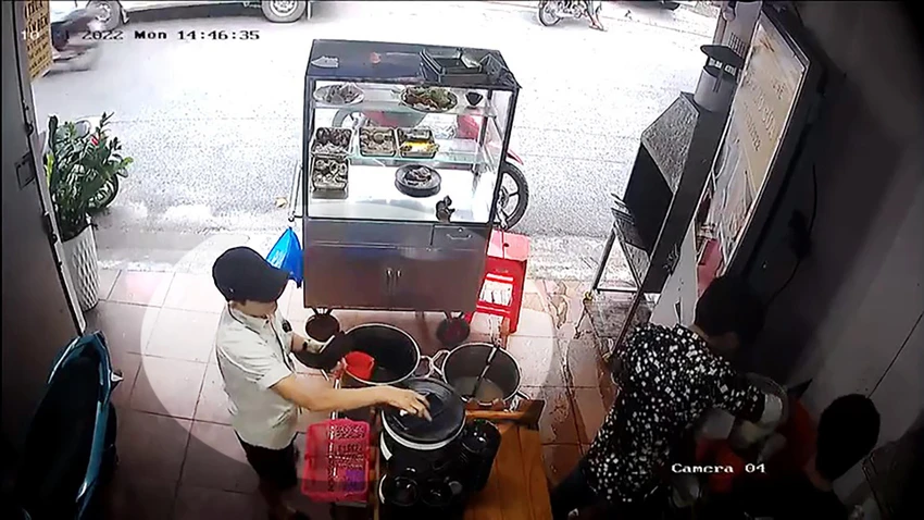 Người phụ nữ tranh thủ chủ quán quay lưng làm cơm thì lấy điện thoại. Ảnh chụp từ clip Người phụ nữ tranh thủ chủ quán quay lưng làm cơm thì lấy điện thoại. Ảnh chụp từ clip