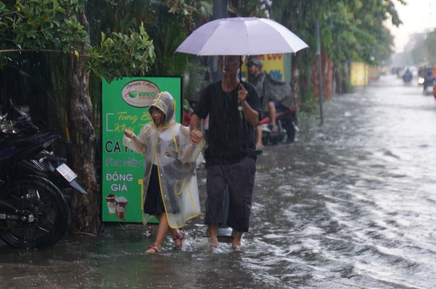 Một số phụ huynh đi rước con về phải đi nép vào lề đường để tránh các vũng nước sâu. Một số phụ huynh đi rước con về phải đi nép vào lề đường để tránh các vũng nước sâu.