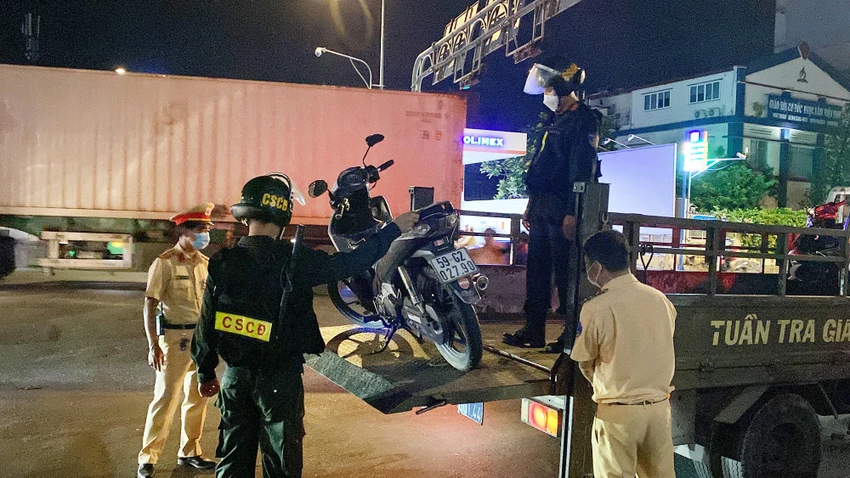 Lực lượng chức năng đưa phương tiện bị tạm giữ lên xe. Ảnh: ĐC Lực lượng chức năng đưa phương tiện bị tạm giữ lên xe. Ảnh: ĐC