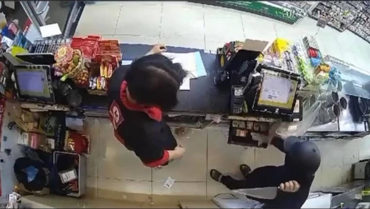 Hình ảnh vụ cướp được camera cửa hàng tiện ích Circle K ghi lại. Nghi phạm tay trái cầm dao đe dọa nhân viên cửa hàng, tay phải cướp tiền. Ảnh: CACC Hình ảnh vụ cướp được camera cửa hàng tiện ích Circle K ghi lại. Nghi phạm tay trái cầm dao đe dọa nhân viên cửa hàng, tay phải cướp tiền. Ảnh: CACC