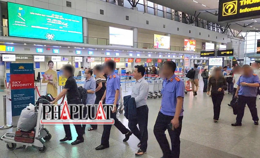 Hai người đàn ông với hai tay bị trùm áo được cán bộ VKSND Tối cao áp tải ra sân bay nhanh chóng. Ảnh: MINH TRƯỜNG