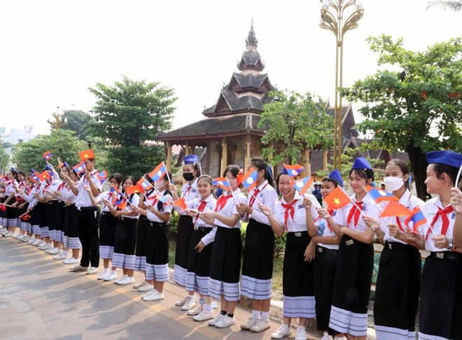 Các cháu thiếu nhi thủ đô Vientiane vẫy cờ hoa đón Chủ tịch nước Võ Văn Thưởng sang thăm chính thức Lào. Ảnh: TTXVN