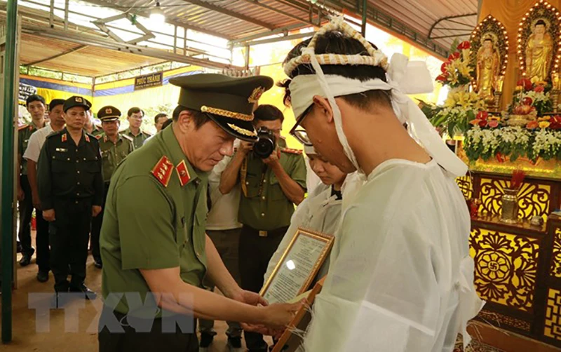 Thứ trưởng Bộ Công an Lương Tam Quang trao quyết định truy thăng cấp bậc hàm từ Đại uý lên Thiếu tá đối với chiến sĩ Hoàng Trung, hy sinh trong vụ tấn công bằng súng tại trụ sở xã Ea Tiêu và xã Ea Ktur, huyện Cư Kuin, tỉnh Đắk Lắk cho thân nhân gia đình. Ảnh: TTXVN