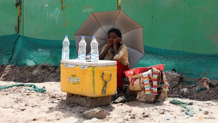 Một cô gái bán nước dùng ô che nắng ở New Delhi, Ấn Độ, ngày 27-4. Ảnh: REUTERS Một cô gái bán nước dùng ô che nắng ở New Delhi, Ấn Độ, ngày 27-4. Ảnh: REUTERS