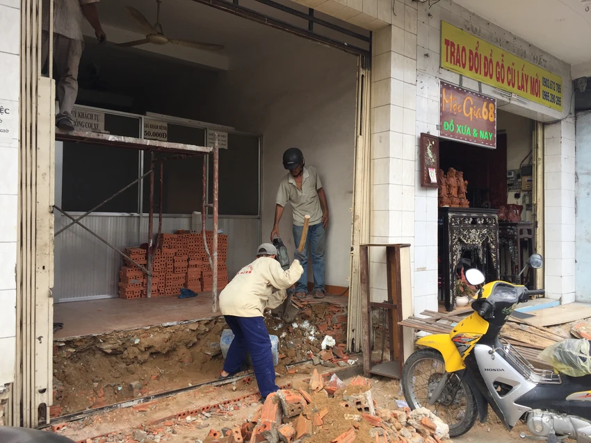 Nhà 63 Trường Chinh (quận Tân Bình, TP.HCM) đã bị đập bỏ bậc thềm hồi tuần trước. Hiện nhà này đã thuê thợ đến để đập sàn nhà, thi công bậc thềm mới phía trong nhà để không lấn chiếm vỉa hè. Ảnh: QUỲNH NHƯ