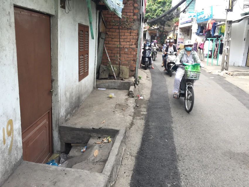Rất cần hạ tầng chỉn chu để người dân không phải trèo lên hay "tuột xuống" nhà mình. Một ngôi nhà trên đường Bùi Đình Túy, quận Bình Thạnh có một nửa cửa thấp hơn mặt đường. Ảnh: Quỳnh Như