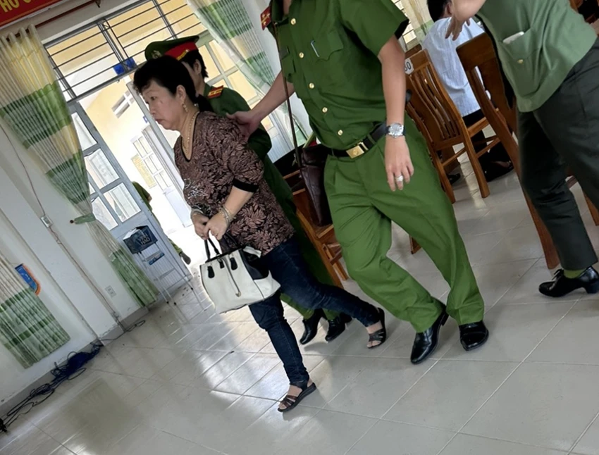 Nữ kế toán trưởng bị dẫn giải ra xe. Ảnh: PĐ Nữ kế toán trưởng bị dẫn giải ra xe. Ảnh: PĐ