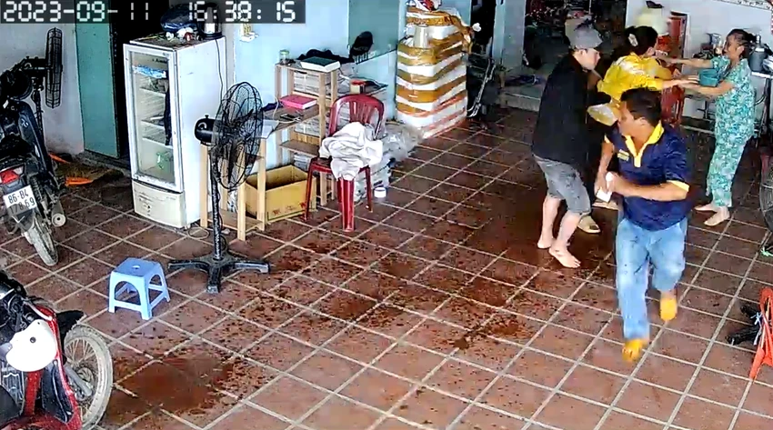 Người mẹ (góc phải của ảnh) can ngăn nhưng hai con trai vẫn đổ xăng ra khắp nơi. Ảnh cắt từ camera. Người mẹ (góc phải của ảnh) can ngăn nhưng hai con trai vẫn đổ xăng ra khắp nơi. Ảnh cắt từ camera.