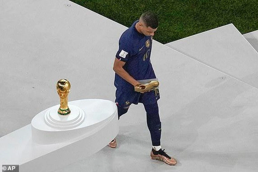 Mbappe cầm chiếc giày vàng đi qua chiếc cúp vô địch World Cup. ẢNH: AP Mbappe cầm chiếc giày vàng đi qua chiếc cúp vô địch World Cup. ẢNH: AP