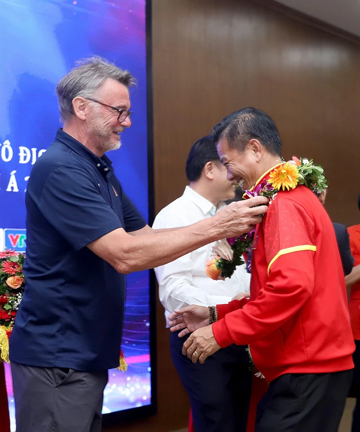 HLV Philippe Troussie đeo dây hoa chúc mừng HLV Hoàng Anh Tuấn. ẢNH: VFF