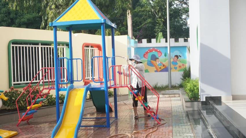Nhân viên lau chùi khu vực sân chơi để trẻ vui chơi đảm bảo vệ sinh.