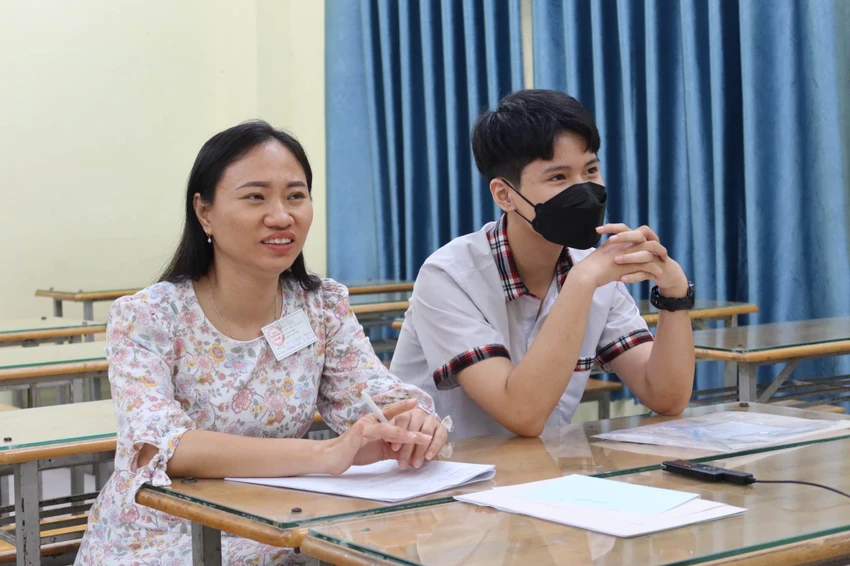Hoàng Anh cùng cán bộ viết hộ bài trước giờ thi. Ảnh: TRẦN MINH Hoàng Anh cùng cán bộ viết hộ bài trước giờ thi. Ảnh: TRẦN MINH