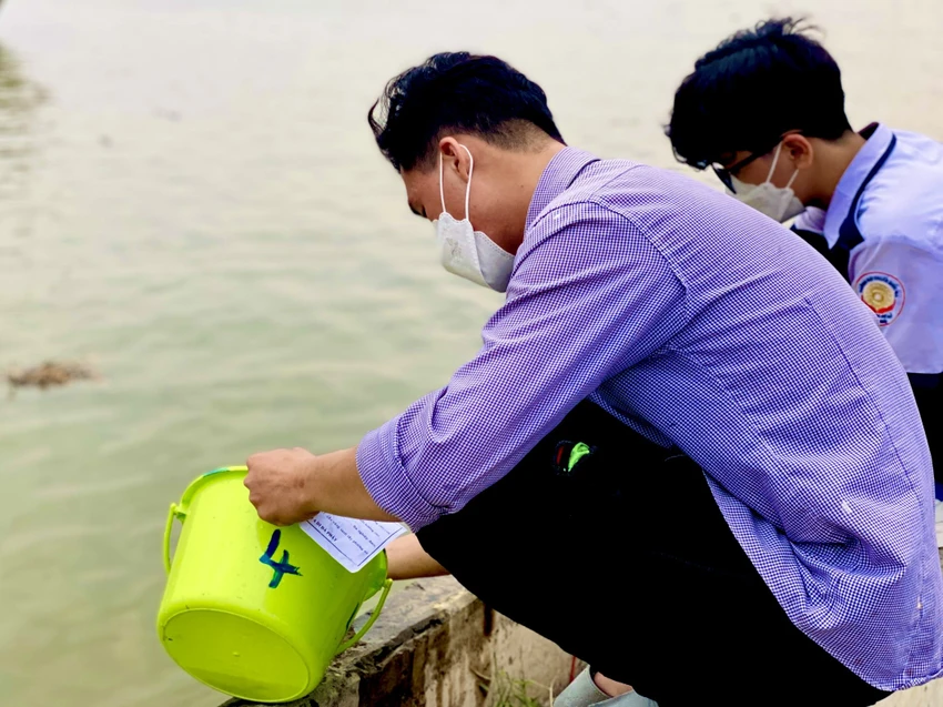 Anh Đạt cùng em trai mang cá ra bờ sông để thả. Ảnh: T.N Anh Đạt cùng em trai mang cá ra bờ sông để thả. Ảnh: T.N