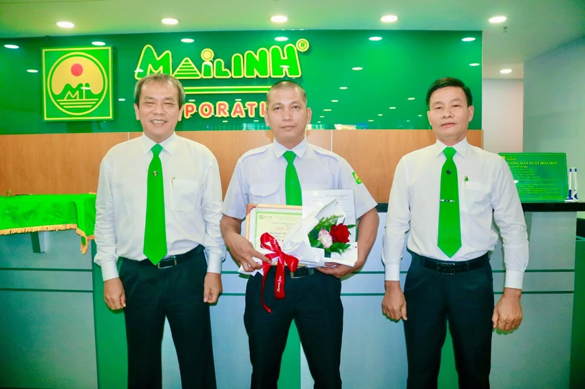 Ông Trương Quang Mẫn (trái) - Phó Tổng giám đốc Thường trực và ông Võ Quốc Hùng - Chủ tịch Công đoàn Tập đoàn Mai Linh trao bằng khen và hoa cho lái xe Nguyễn Minh Hải (giữa).