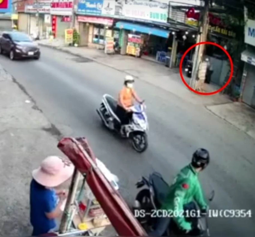 Người mặc áo xe ôm công nghệ đứng đợi đồng bọn đang lấy trộm xe máy bên đối diện đường vào sáng 28-3. Ảnh: Cắt từ clip Người mặc áo xe ôm công nghệ đứng đợi đồng bọn đang lấy trộm xe máy bên đối diện đường vào sáng 28-3. Ảnh: Cắt từ clip