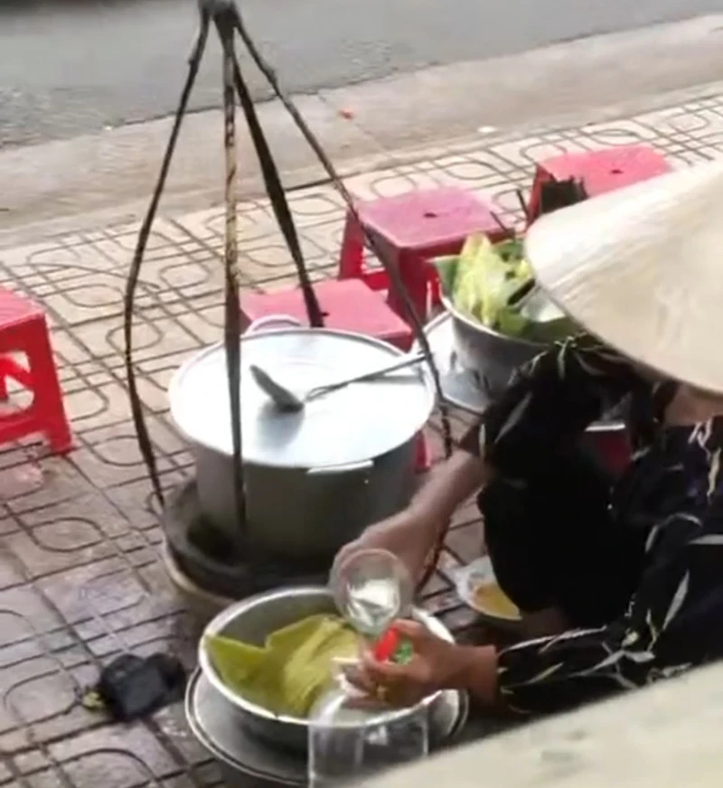 Người phụ nữ đổ ca nước thừa vào bình. Ảnh cắt từ clip Người phụ nữ đổ ca nước thừa vào bình. Ảnh cắt từ clip