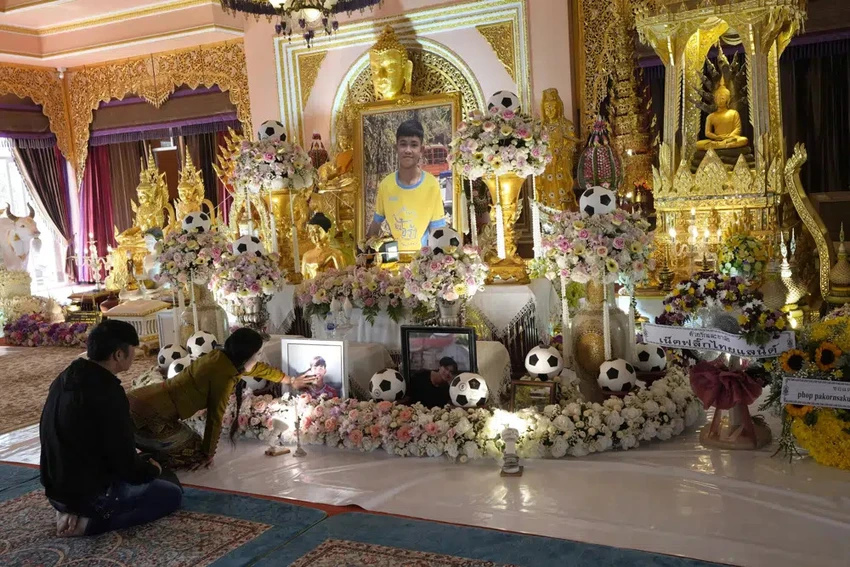 Thành viên gia đình của cầu thủ nhí Thái Lan Duangphet Phromthep chạm vào di ảnh cậu trong lễ tang. ẢNh: AP