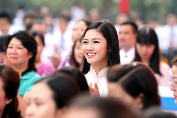 Cô ngồi cùng các thầy cô, theo dõi lễ khai giảng. Cô hòa mình vào không khí của các tiết mục văn nghệ trong chương trình.