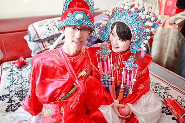 [Caption]Trang phục cưới của người Trung Quốc là màu đỏ, màu được cho là mang lại may mắn cho việc hỷ sự. Theo truyền thống, cô dâu Trung Quốc đội tấm vải đỏ trên đầu, và khi chú rể tự tay nhấc chiếc khăn này ra, hai người chính thức là vợ chồng, sau lễ vọng bái gia tiên. Khác với người Nhật, Trung Quốc quan niệm màu trắng là màu tang tóc nên hết sức tránh màu này trong những dịp vui.