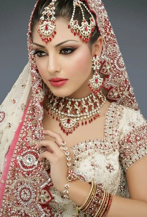 [Caption]Trong văn hóa Ấn Độ, váy cưới truyền thống của cô dâu thường là màu hồng hoặc màu đỏ. Theo phong tục Solah Shringar, trang phục cưới sẽ thường đi kèm theo 16 phụ kiện và đồ trang sức. Ngoài ra, cô dâu vùng phía Bắc Ấn Độ còn có phong tục chấm đỏ giữa trán (gọi là bindi) khi về nhà chồng.