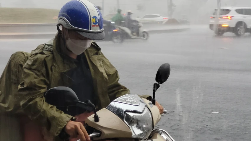 Một người dân vội vã tấp vào lề để mặc áo mưa